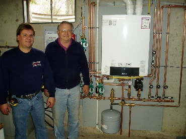 Hannabery HVAC installation mechanic and Mr. McClure standing next to his new Buderus side-wall vented Boiler with a 50-gallon Indirect Hot Water Tank.